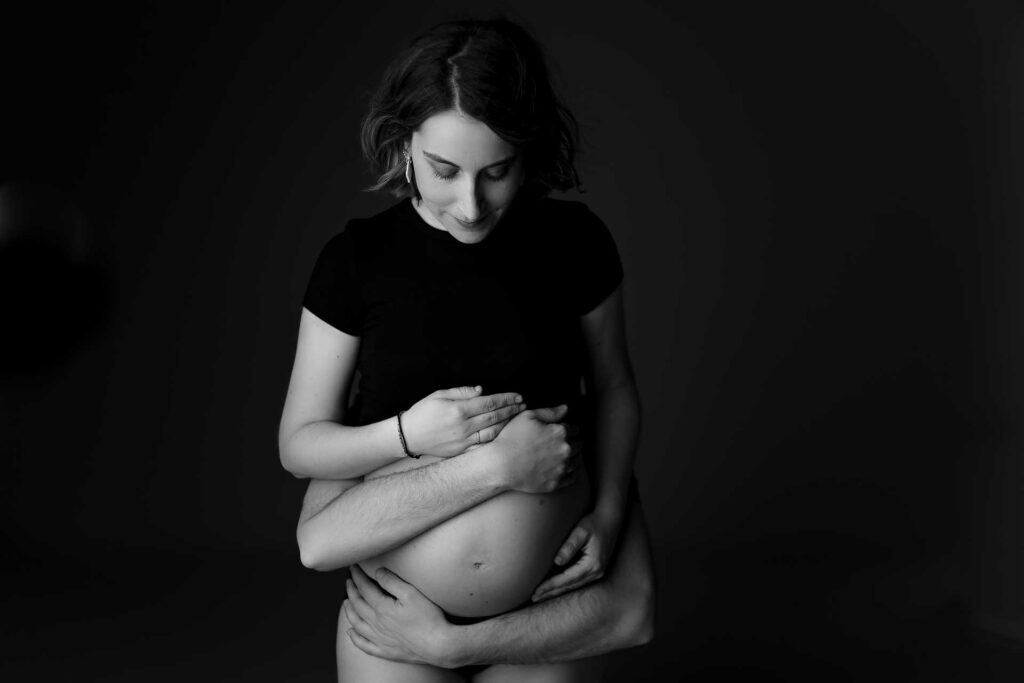 fotografia de pareja joven a embarazada en estudio abrazando tripa de premama